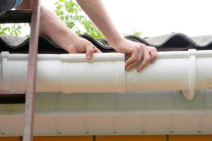 Contractor installing plastic roof gutter pipeline