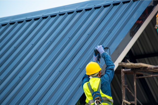 Metal roof installation by a worker with a hard hat