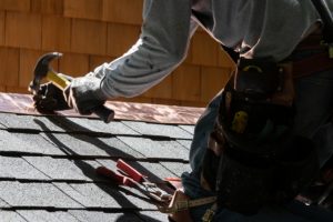 Worker Repairing roof with a hammer and nails